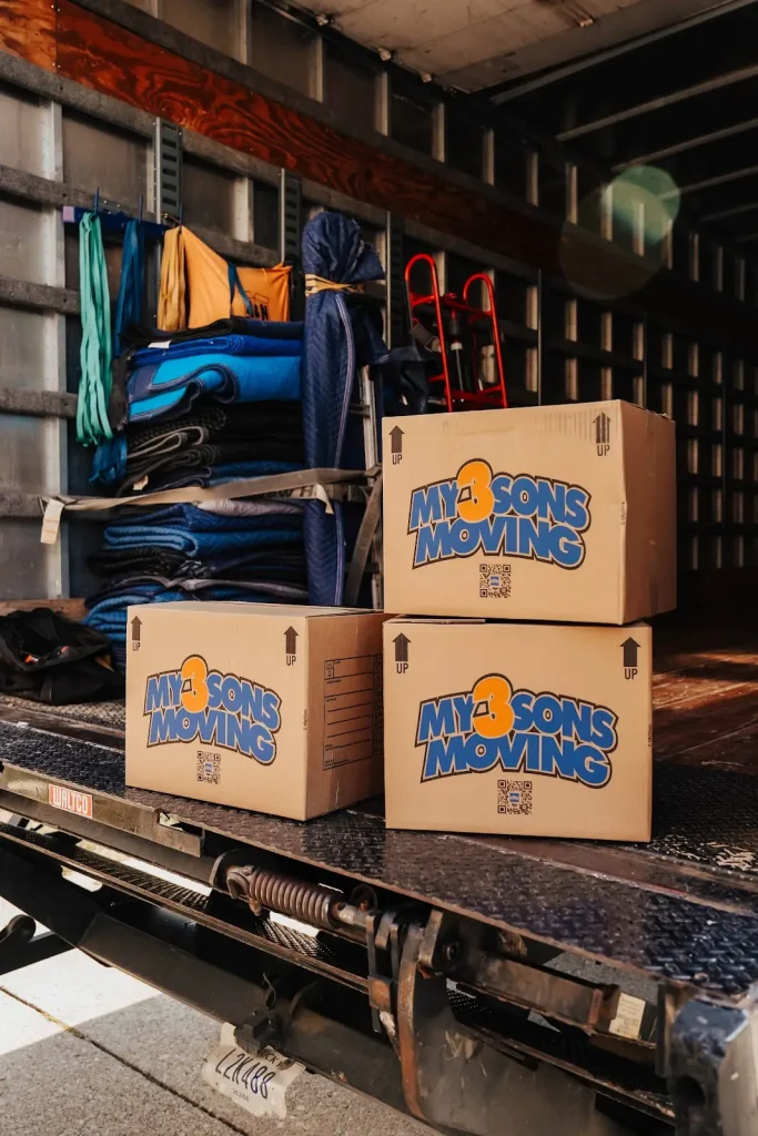 Labeled moving boxes secured inside a moving truck with moving blankets and equipment ready for transport.